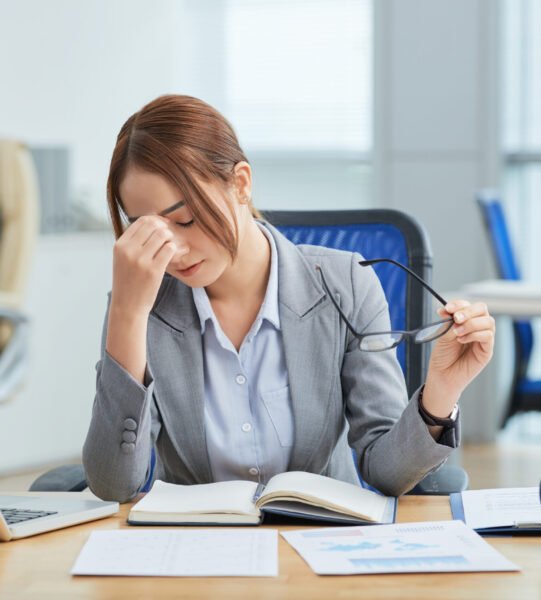 plano-medio-joven-mujer-asiatica-sentada-escritorio-oficina-frotandose-nariz